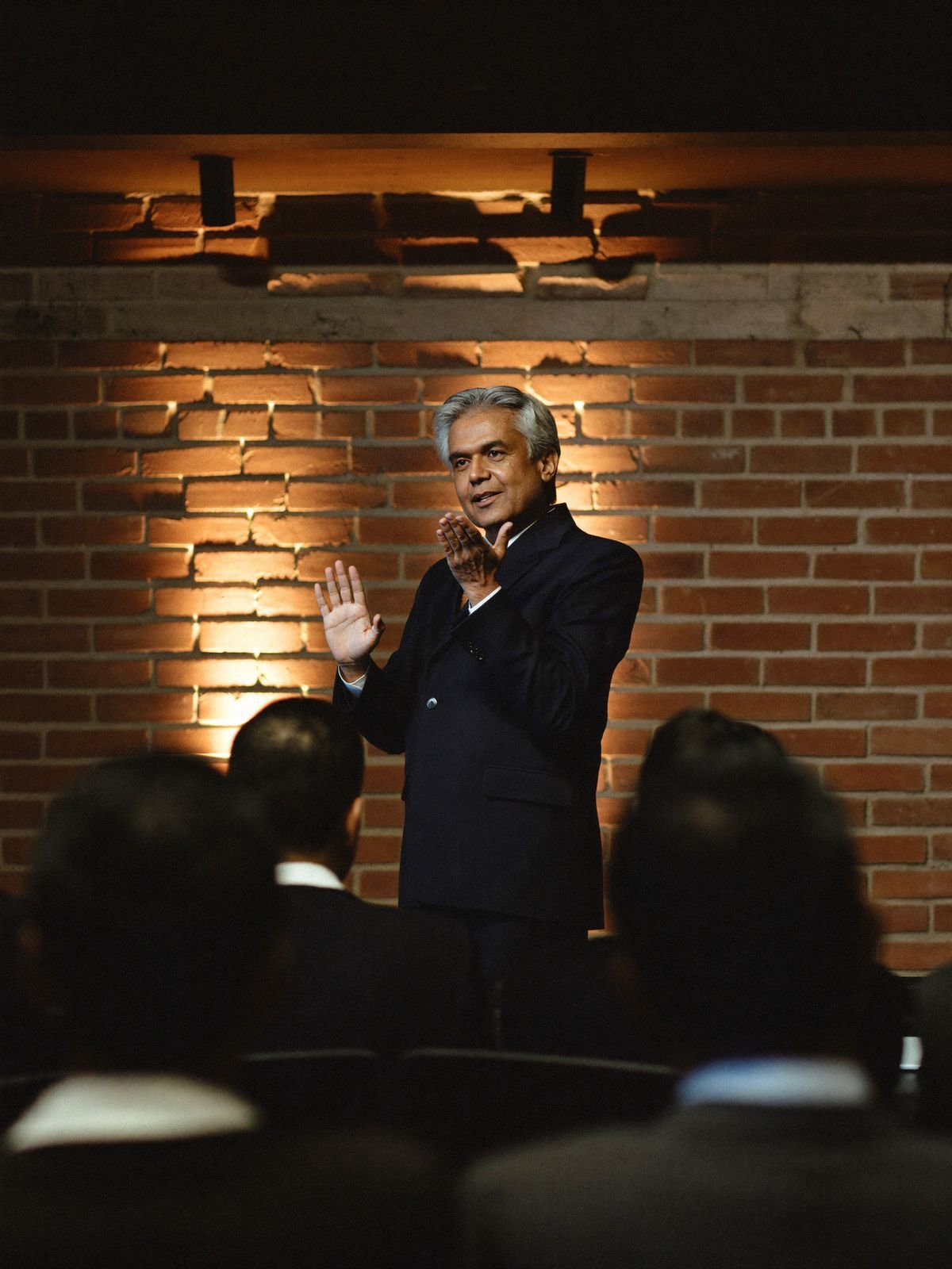 Corporate trainer speaking to an audience in a warm brick venue